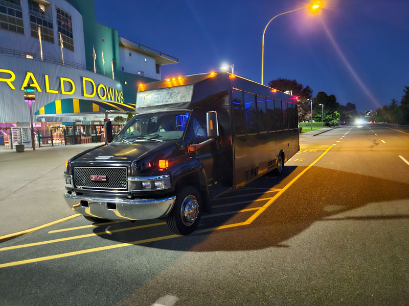 Seattle Party Limo black GMC party bus parked at Emerald Downs at dusk